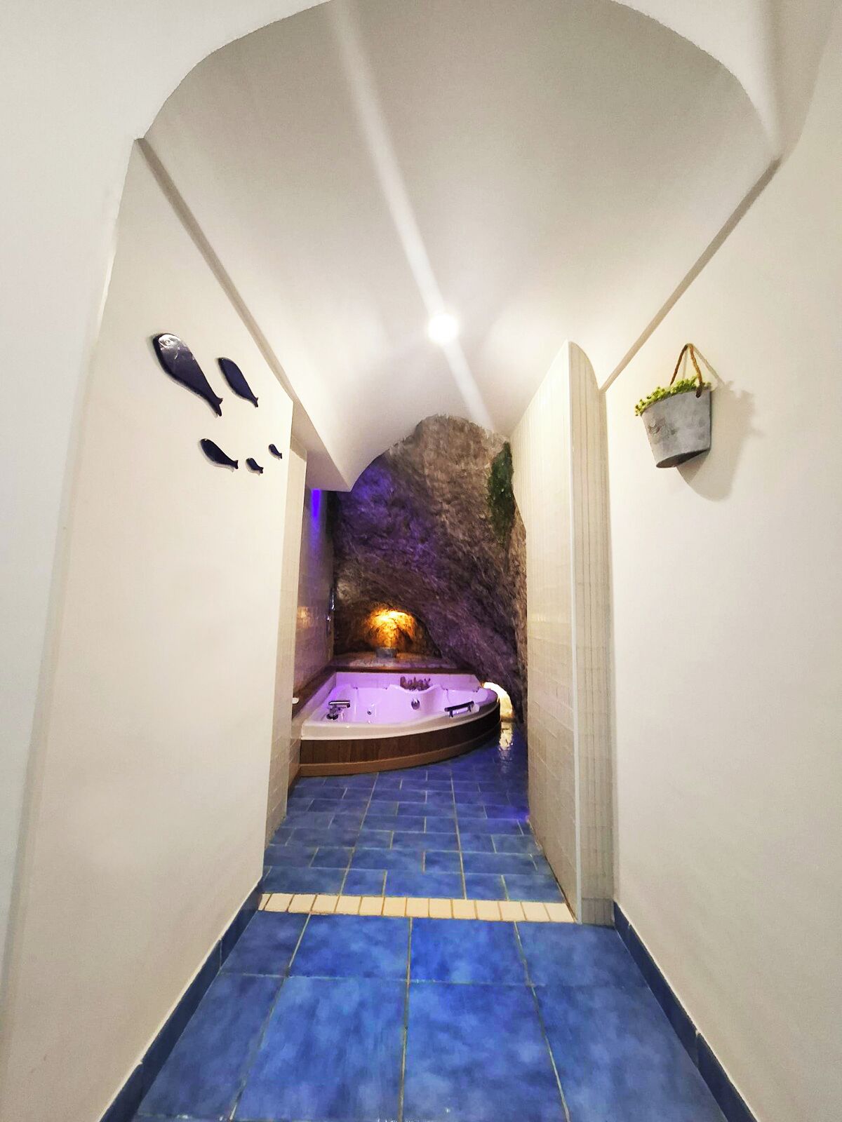 Corredor estreito com piso azul-cerâmico que leva a uma área de spa com hidromassagem.