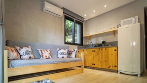 A compact living space with a sofa, a small kitchen area, and a built-in bench. - Bom pra Cachorro (Morro de São Paulo)