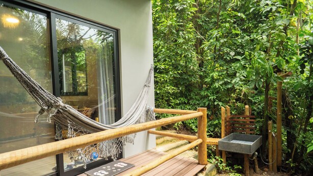 A wooden deck with a hammock, a wooden bench, and a stone sink. - Bom pra Cachorro (Morro de São Paulo)