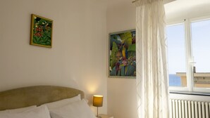Una habitación de hotel con una cama, una mesita de noche con lámpara y dos cuadros en la pared.