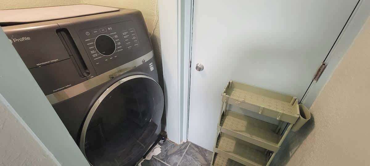 A compact laundry area with a front-loading washing machine and a metal drying rack.