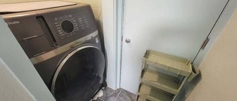 A compact laundry area with a front-loading washing machine and a metal drying rack.