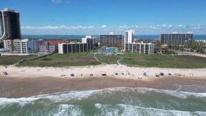 A beachside resort with multiple high-rise buildings, a sandy beach, and a view of the ocean. - Beachfront Hotspot - New Furnishings - Pool - 1st Floor (South Padre Island)