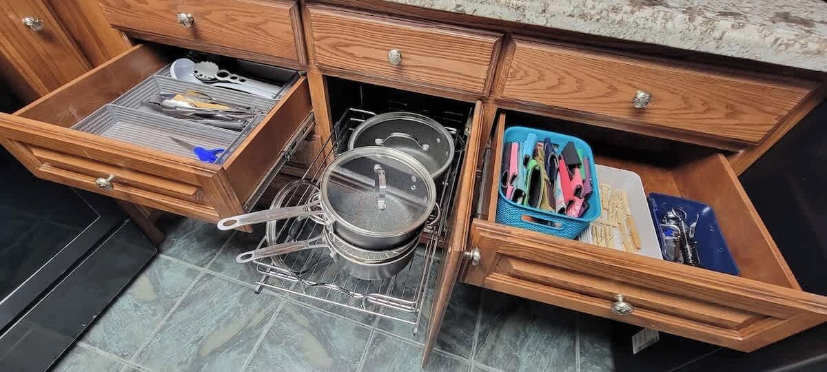 Een keuken met houten kastjes, een inbouwoven en een afwasschaal.