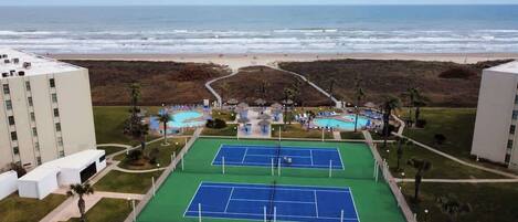 Complejo de canchas de tenis con vista a la playa y al océano.