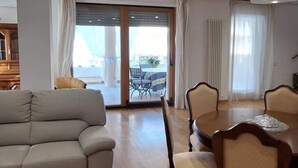A modern living room with a sofa, dining table, and chairs. There is a sliding glass door leading to an outdoor area. - Semi-detached house-Francavilla al mare (Francavilla al Mare)