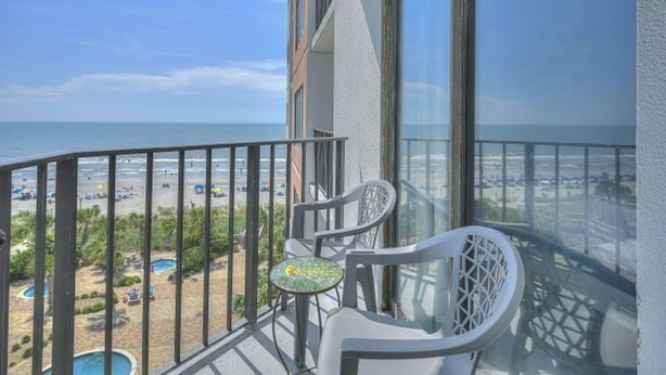 A balcony with a view of the beach and pool.