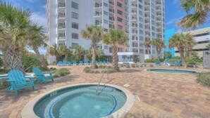 A pool area with two hot tubs, lounge chairs, and palm trees.