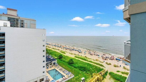 A view of a beach with a swimming pool and lounge chairs.