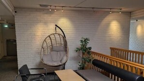 A modern lounge area with a hanging chair, a bench, and a table.