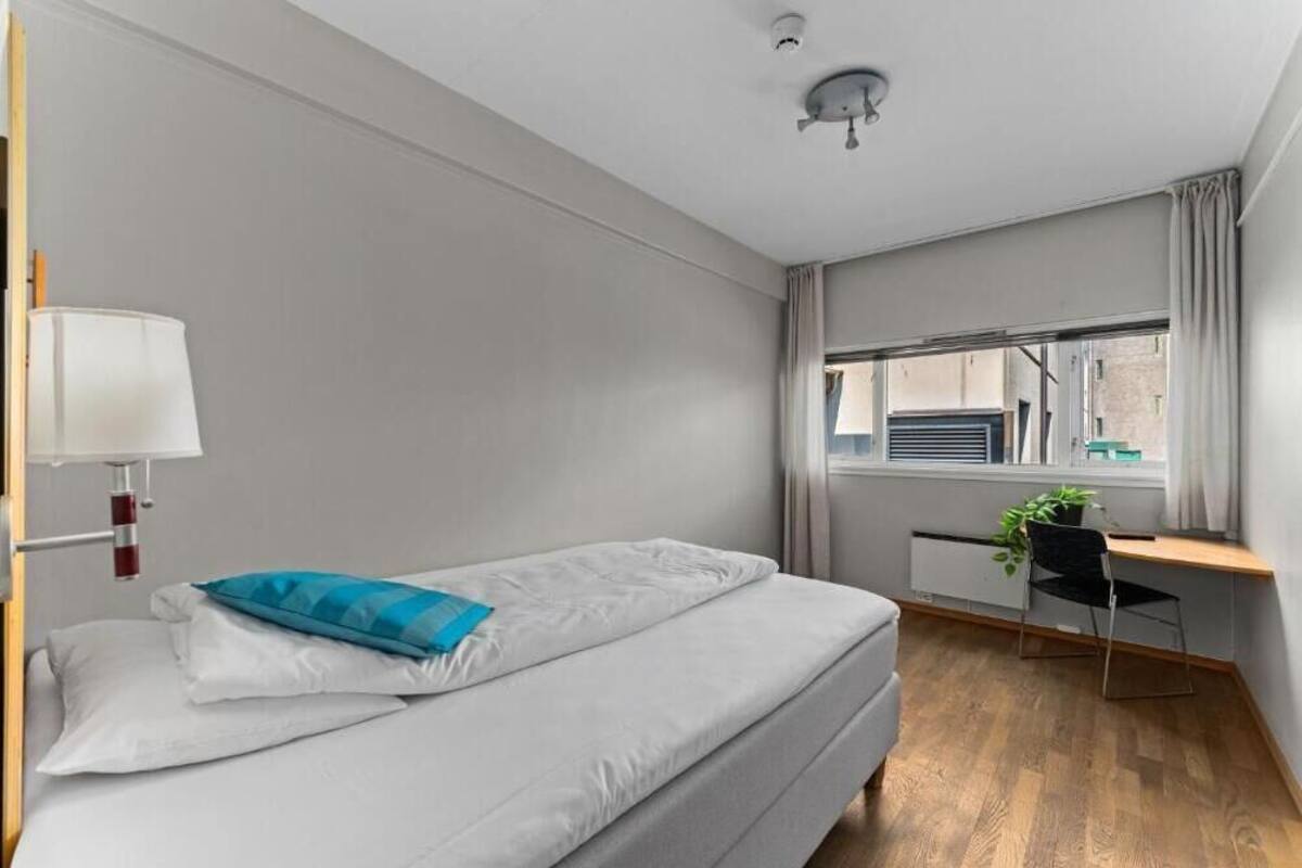 Un dormitorio moderno con cama, escritorio y ventana.