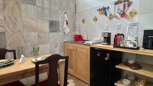 Une cuisine compacte avec une table à manger en bois, un réfrigérateur noir et un pare-feu en carreaux.