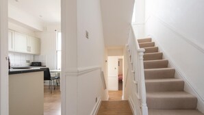 A staircase leading to a landing with a kitchen area visible in the background. - Split-level spacious family apartment (London)