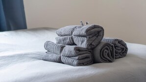 A neatly made bed with folded towels and a framed picture on the wall. - Split-level spacious family apartment (London)