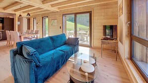 Ein geräumiges Wohnzimmer mit einem blauen Sofa, einem Glastisch und einem Fernseher auf einem Holzboden.