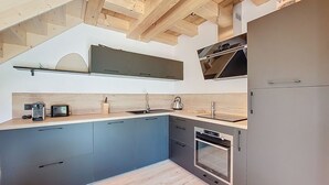Eine moderne Küche mit Holzbalken, einem eingebauten Backofen und einem Edelstahl-Kühlschrank.