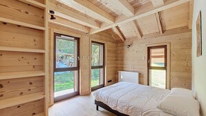 Ein Schlafzimmer einer Holzhütte mit einem Bett, zwei Fenstern und einer eingebauten Bank.