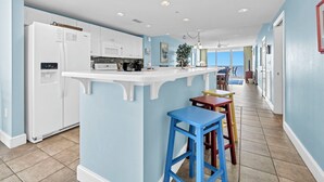 Una cocina moderna con electrodomésticos blancos, una isla central y paredes azules.
