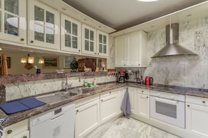 A kitchen with white cabinets, a stainless steel range hood, a granite countertop, and a dishwasher.