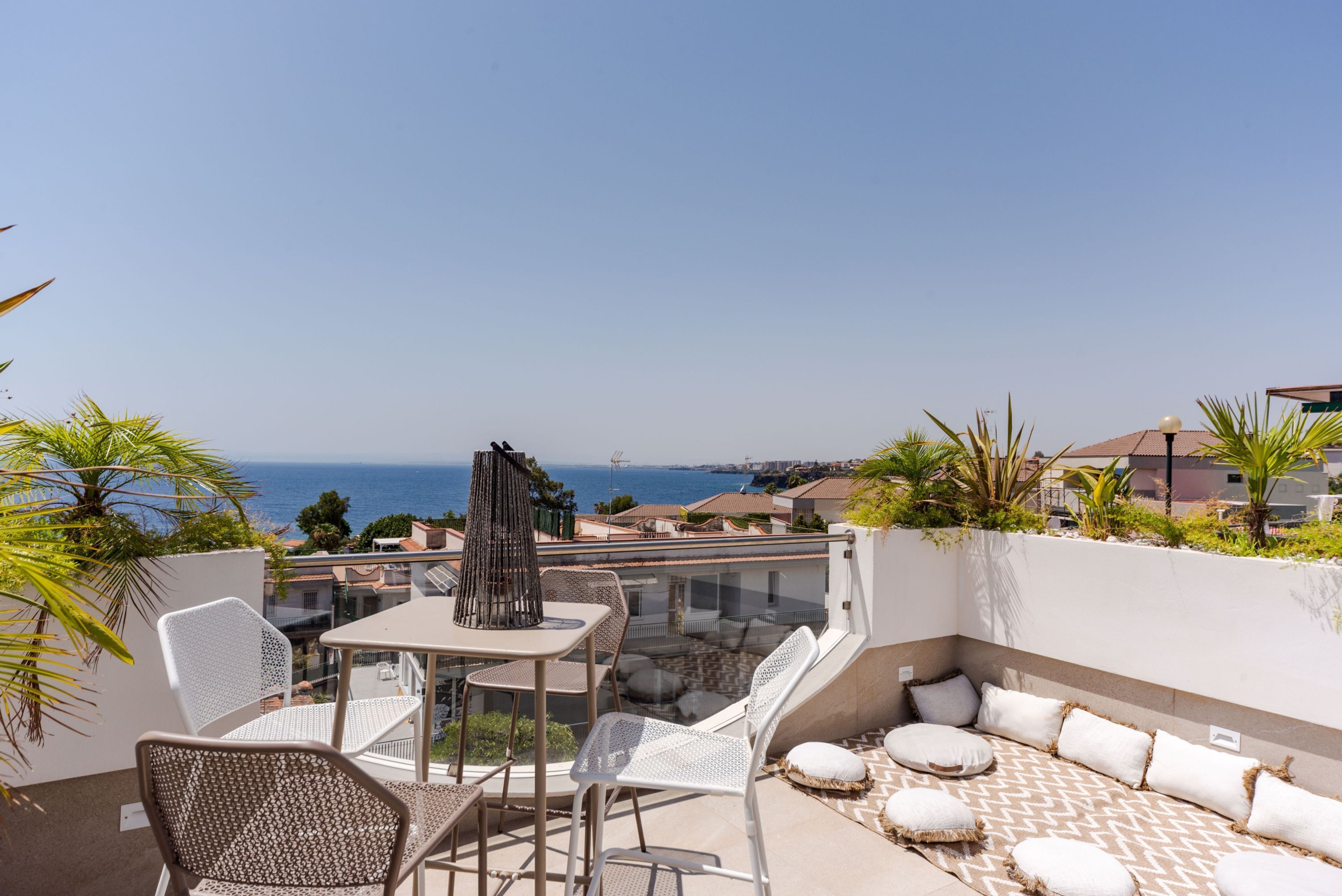 Un balcon avec une table et des chaises, un coin salon confortable et une vue sur la mer.