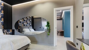 A modern bedroom with a curved mirror, a bed, a desk, and a chair. - Terrace Jacuzzi - Tropicalia by Wonderful Italy (Aci Castello)