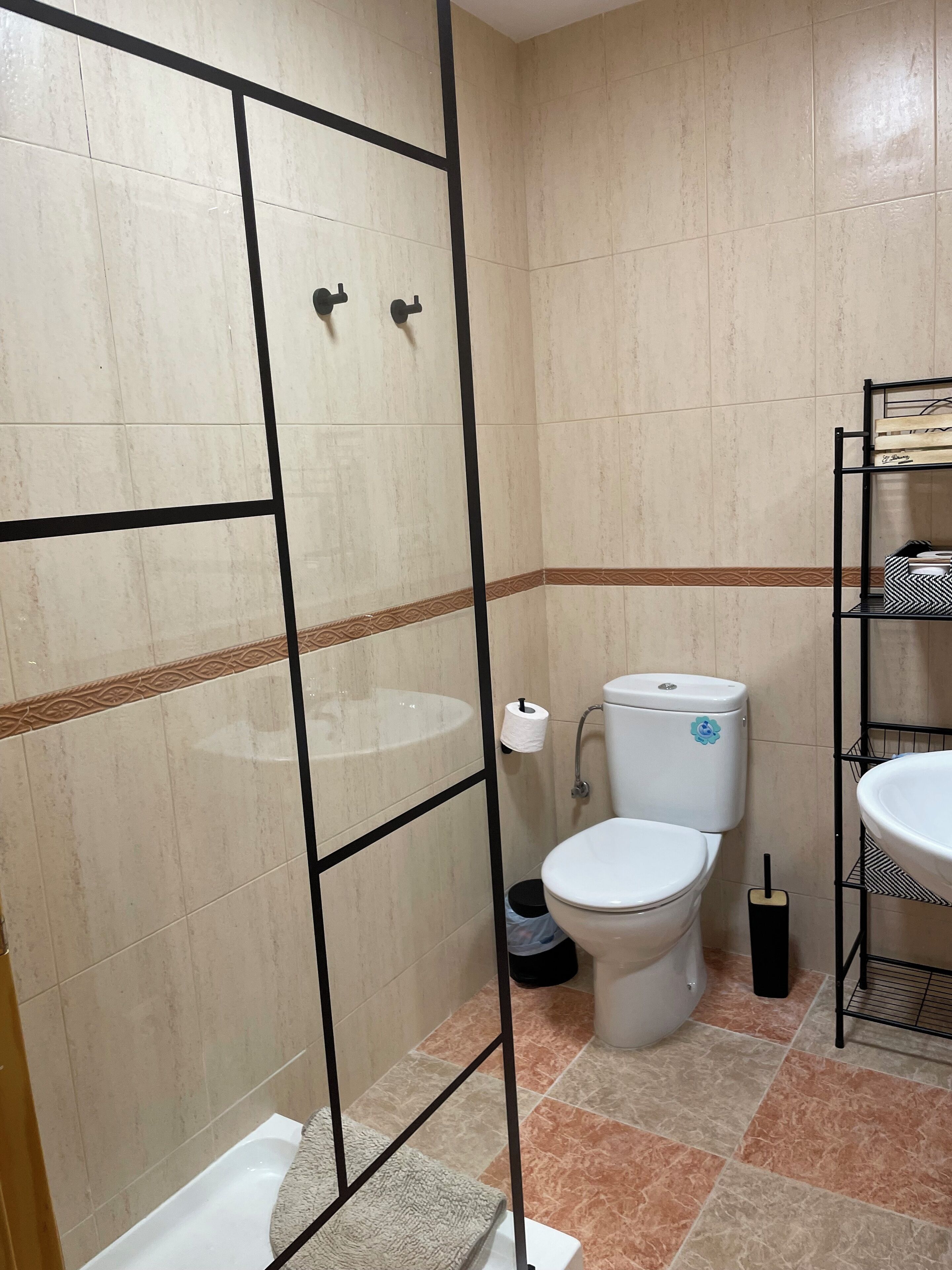 Uma casa de banho com chuveiro, sanita e lavatório.