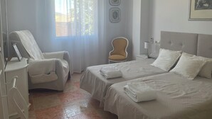 A hotel room with two beds, a chair, a desk, and a window with curtains. - El Mirador de Sierra Mágina II ( ideal for family travel) (Noalejo)