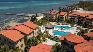 A resort with multiple buildings, a large swimming pool, and a beach. - 2BR Oceanfront Condo w/ Pools, Balcony + Views (San Pedro Town)