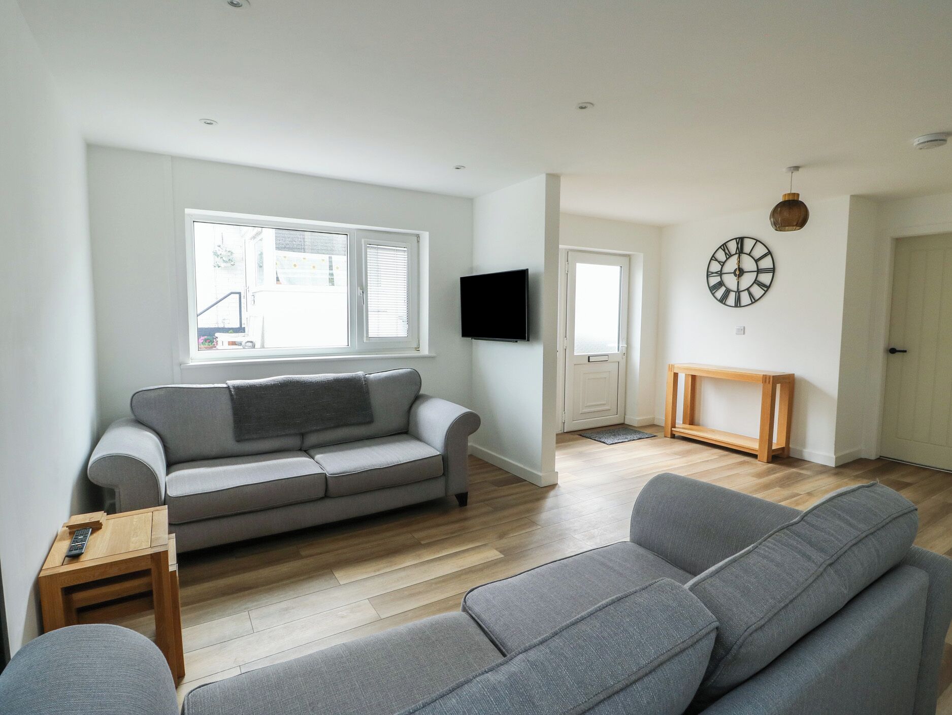 A modern living room with a grey sofa, a wooden coffee table, and a television mounted on the wall.