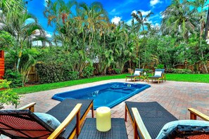 Patio con piscina, sillas de descanso y una vela.