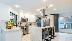 Een moderne keuken met witte kasten, een marmeren eiland en een roestvrijstalen afzuigkap.