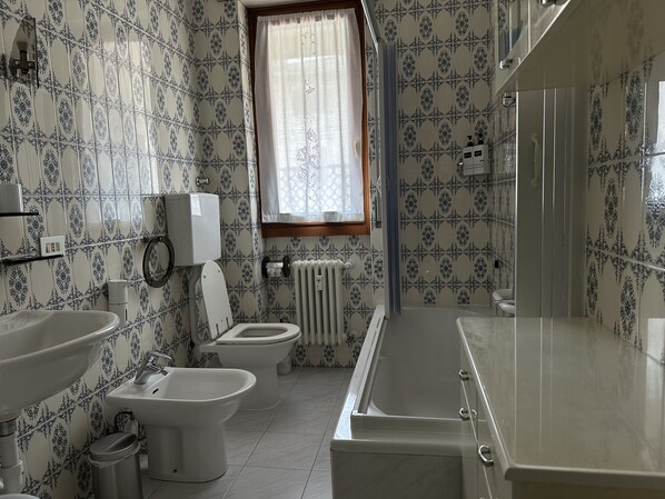 A bathroom with a toilet, bidet, sink, and bathtub.