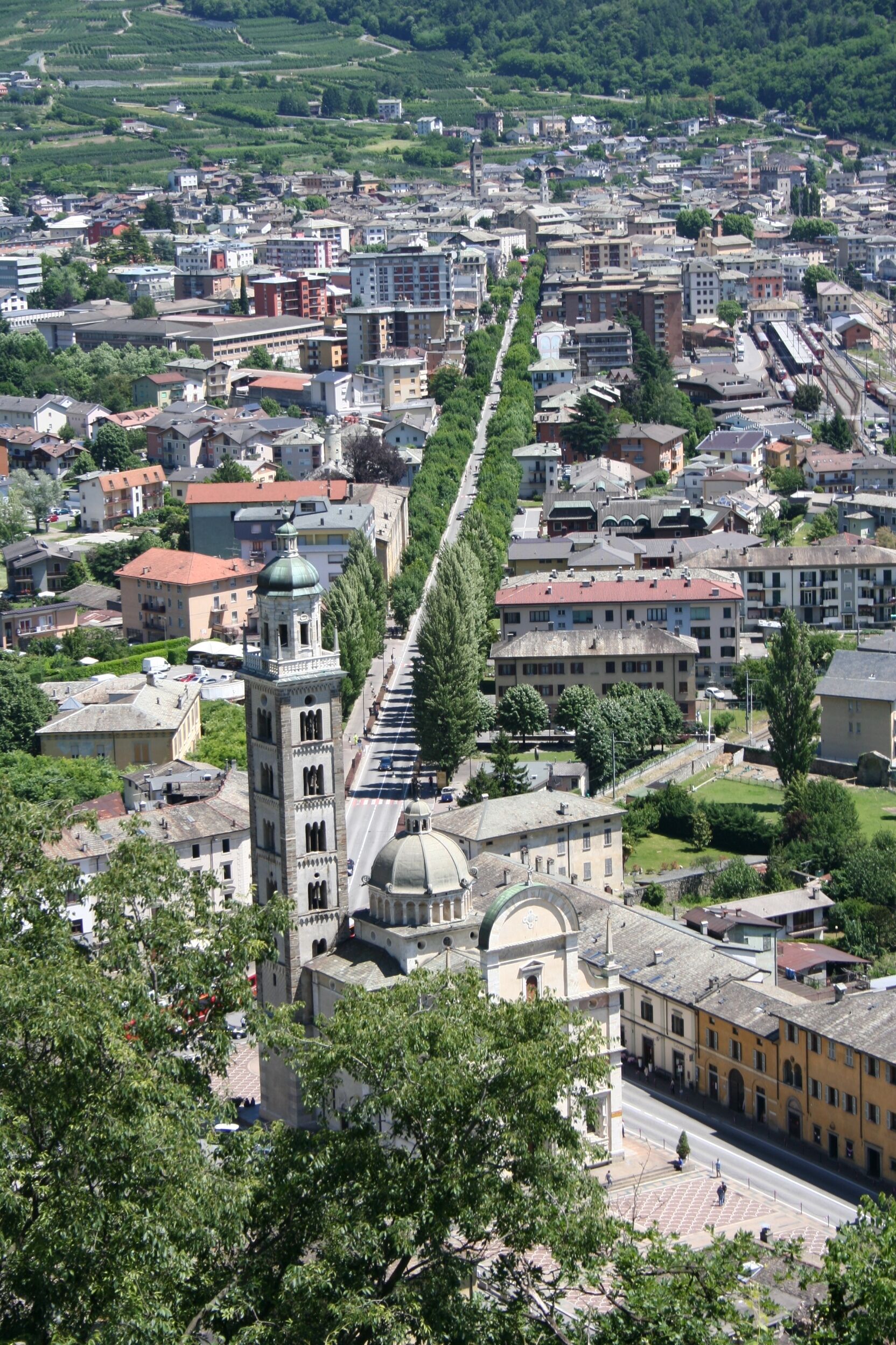 Un paisaje urbano con una torre destacada y una estructura abovedada, rodeado de edificios residenciales y vegetación.