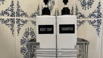 To flasker med sæbe og shampoo i et badeværelse med dekorative blå og hvide fliser.