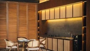A modern kitchen with a dining area, featuring wooden cabinetry, a built-in stove, and a dining table with chairs. - 2bedrooms garden view villa unit 2 (Badung Regency, Bali)