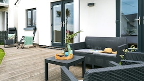 Un patio con mobiliario exterior, una mesa con una botella y una planta, y un sofá.