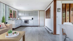 A modern kitchen with white cabinets, a built-in oven, and a dining area with a wooden table and chairs. - Gorgeous home in Erm with house sea view (Erm)