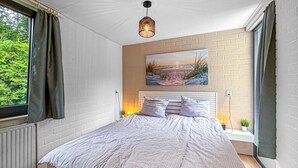 A bedroom with a bed, a painting, a hanging light fixture, and a window with curtains. - Nice home in Dirkshorn with WiFi (Dirkshorn)