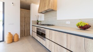Een moderne keuken met houten kastjes, een gasfornuis en een fruitschaal op het aanrecht.