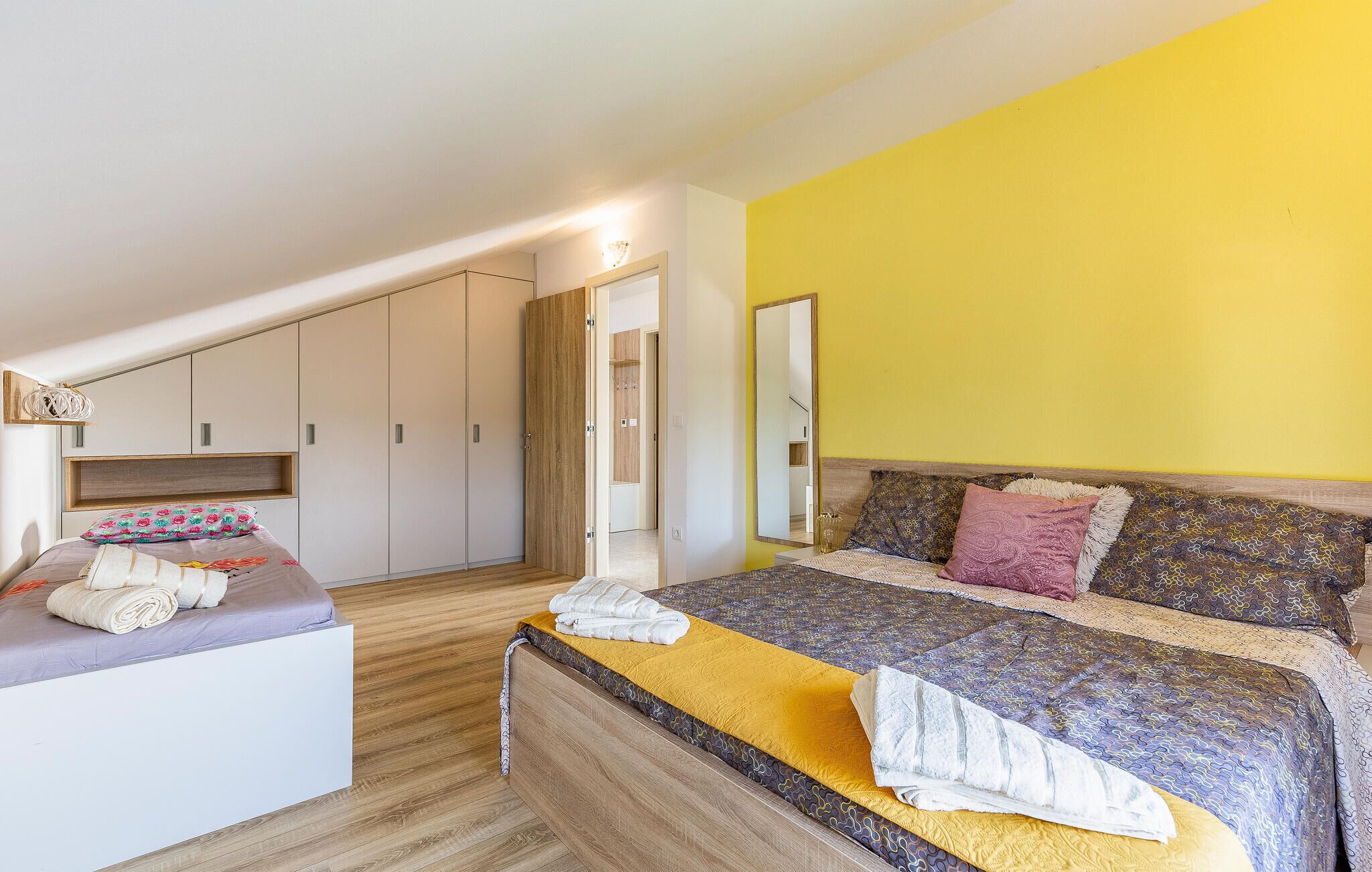 Un dormitorio con cama, mesita de noche, armario y espejo.