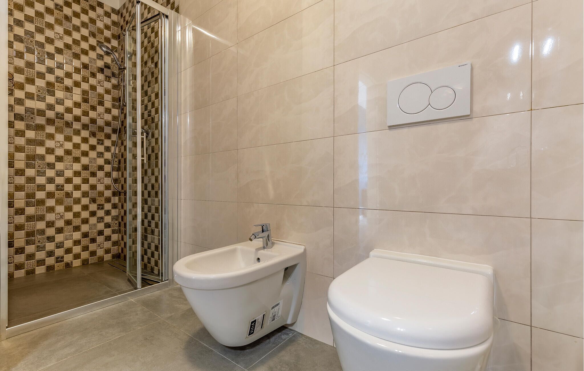 Een badkamer met douche, toilet en hygiëneschuimer.