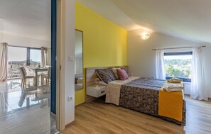 A bedroom with a bed, bedside table, and a window with curtains.