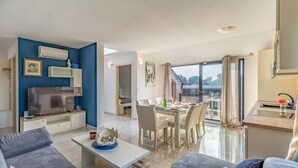 A modern living room with a flat-screen TV, sofa, and dining area with a table set for two. - Stunning apartment in Medulin with WiFi (Medulin)