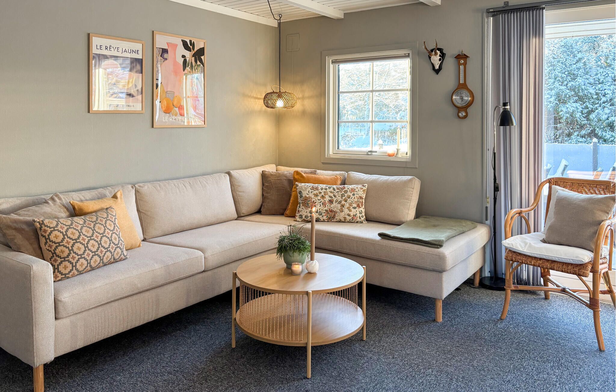A cozy living room with a sectional sofa, a round wooden coffee table, and a wicker chair.