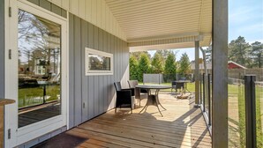 A covered patio with a wooden deck, a table with chairs, and a view of the backyard. - Awesome home in Vejers Strand with WiFi (Vejers Strand)