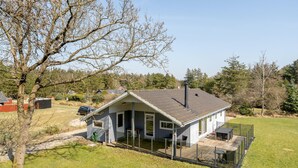 A single-story house with a sloped roof, a covered porch, and a fenced outdoor area with a table and chairs. - Awesome home in Vejers Strand with WiFi (Vejers Strand)