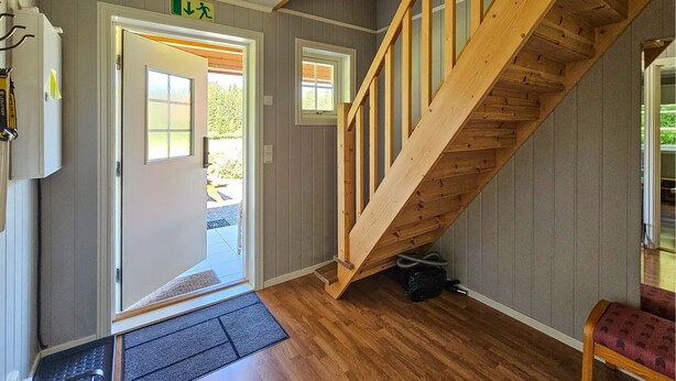 A wooden staircase leading to a second floor, a door with an exit sign, and a doormat at the entrance. - Lovely apartment in Sperrebotn with WiFi (Sperrebotn)