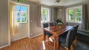 A dining room with a wooden table, six chairs, and a vase of flowers. - Lovely apartment in Sperrebotn with WiFi (Sperrebotn)