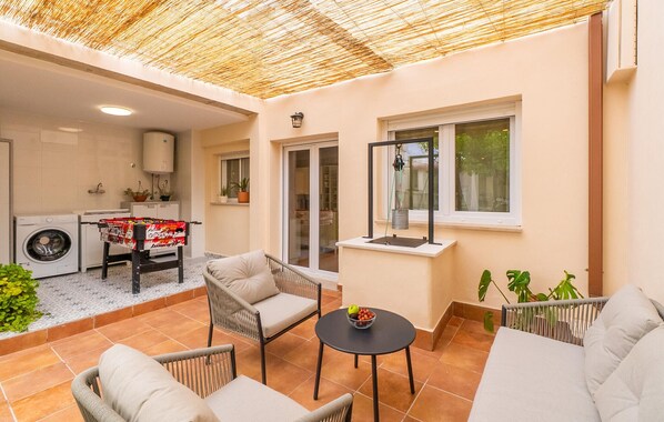 Un espacio habitable compacto con cocina, comedor con mesa y sillas, y zona de estar con sofá y una mesita.