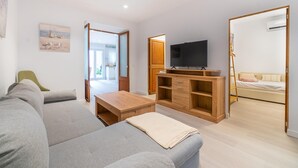 Ein modernes Wohnzimmer mit grauem Sofa, einer Holz-Unterhaltungseinrichtung und einem Fernseher.